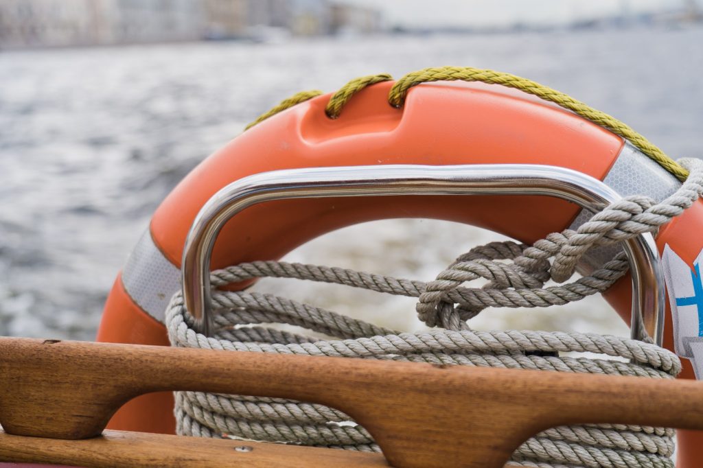 Salvagente legato da una corda alla barca per indicare le attrezzatre che non possono mancare quando si naviga in mare aperto, in lontananza si intravede il mare