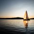 8 tipi di amici da non portare con sé durante una vacanza in barca al tramonto in mare aperto, in lontananza si vedono delle isole e l'acqua del mare è molto piatta e calma