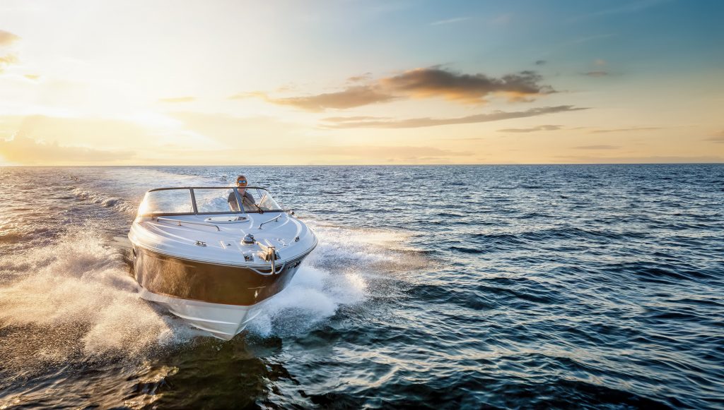 Barca in mare in movimento. Sullo sfondo il tramonto